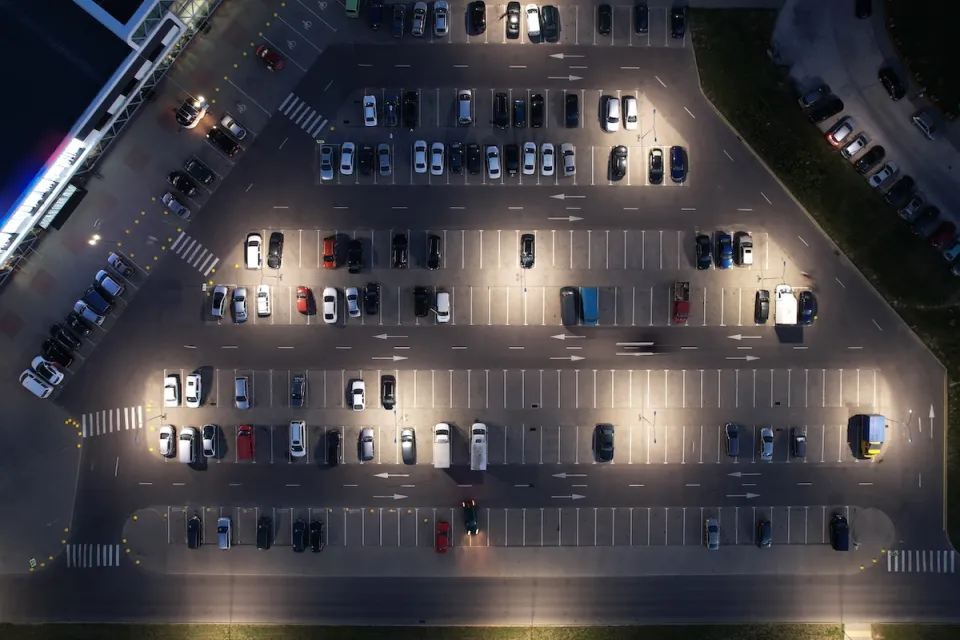 Bird's eye view of half full parking lot at night.